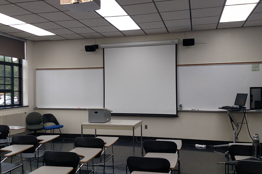 Fenton 179 Front of the classroom with a large projector screen and white board.