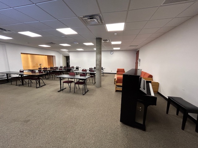 Back of the classroom with student desks arranged in rows. There is a piano next to the right wall.