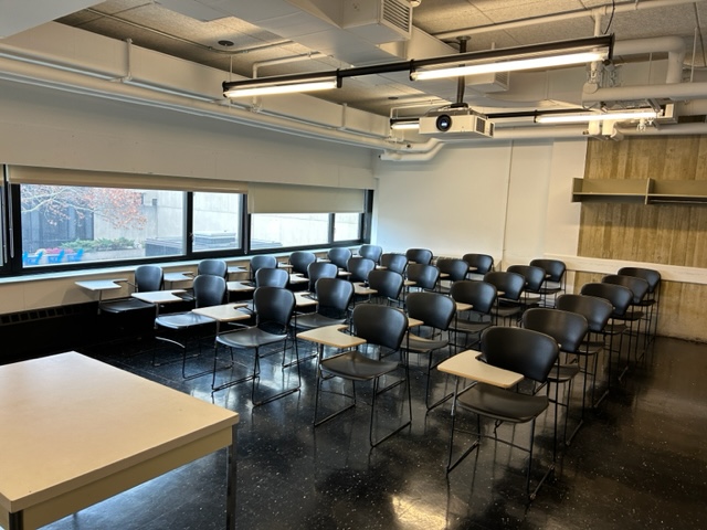 Back of the classroom with student desks and chairs arranged in rows.