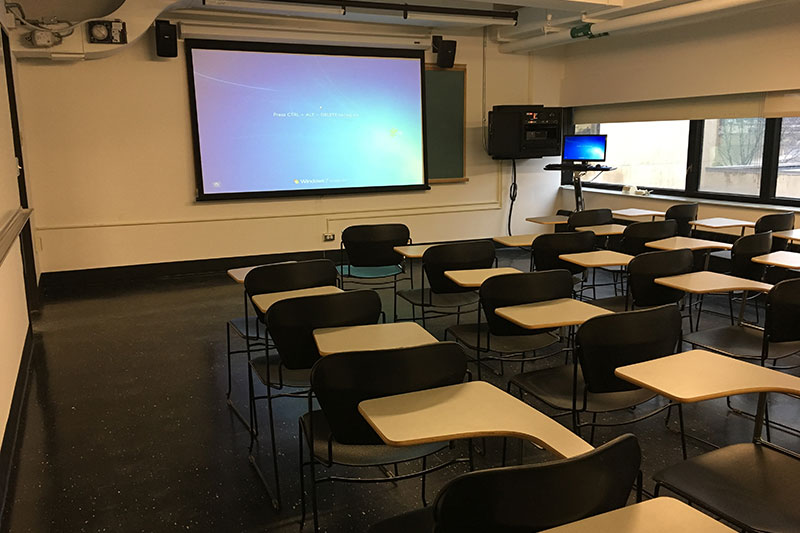 Front of the classroom with a large white board and projector screen.