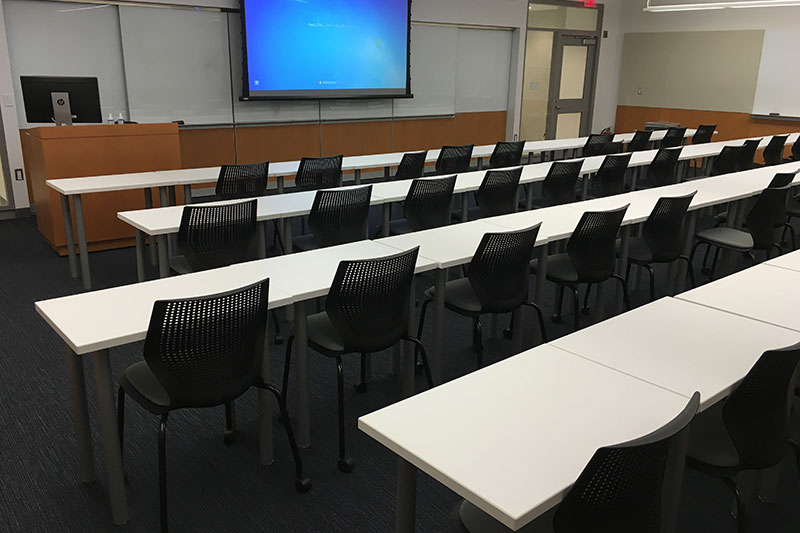 Front of the classroom with a large white board and projector screen.