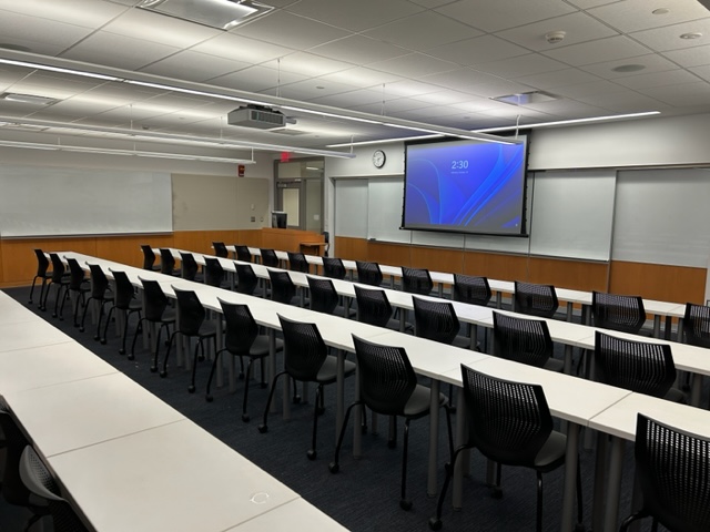 Front of the classroom with a large whiteboard and projector screen.