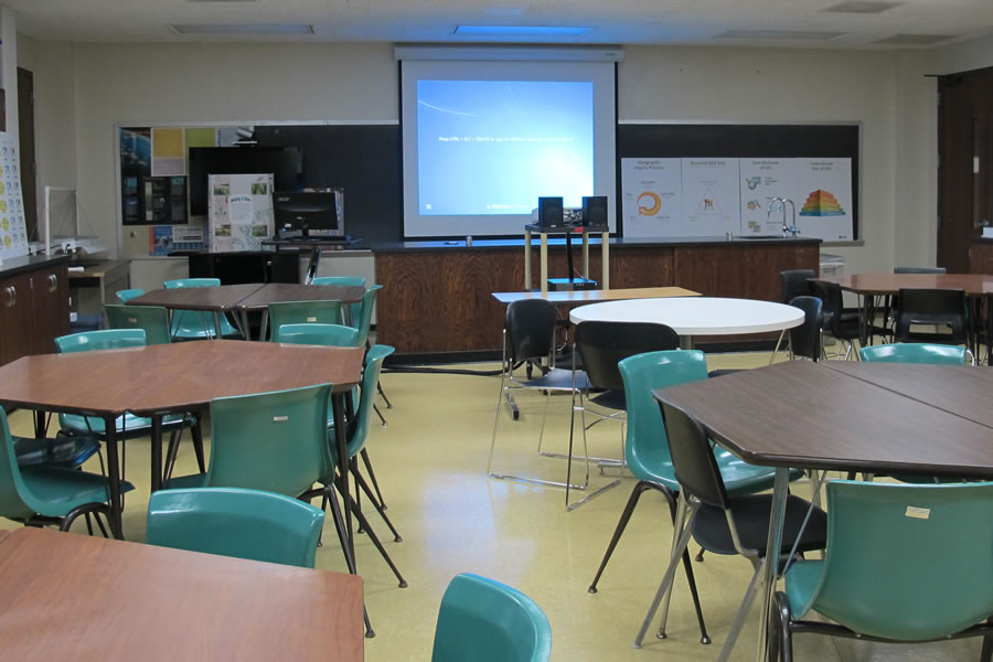 Front of the classroom with a large black board and projector screen.