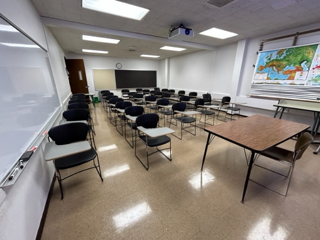 Back of the classroom with student seats arranged in rows and a large map on the wall.