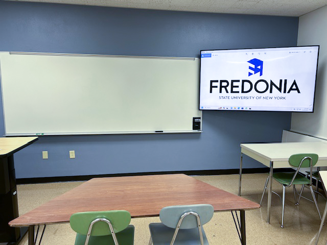 Front of the classroom with a large white board and tv.