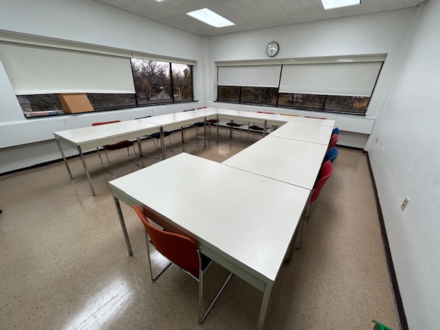 Back of the conference room with tables and chairs in a circle formation.
