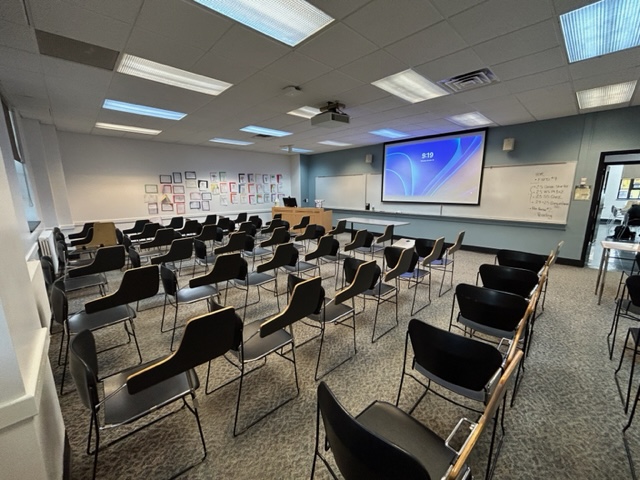 Front of the classroom with a large whiteboard and projector screen.