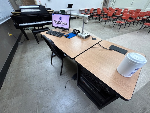 Accessible teachers computer station with an Extron switcher and a grand piano.