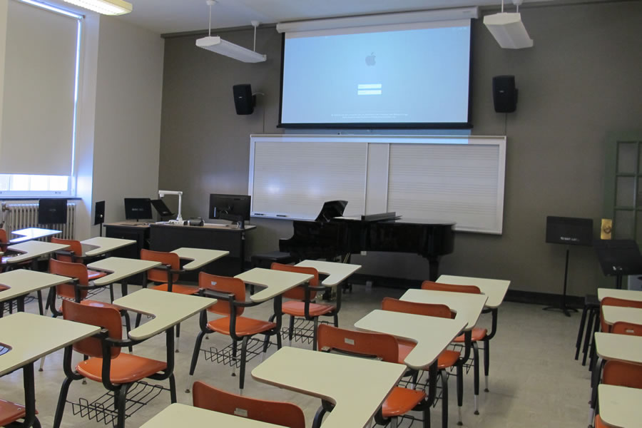 Mason 1022 front of the classroom with a large projector screen and whiteboard.