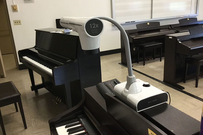 Mason 2020 Smart Classroom teachers station with a piano and a camera.
