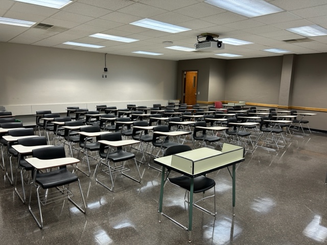 Back of the classroom with student desks and chairs in rows.