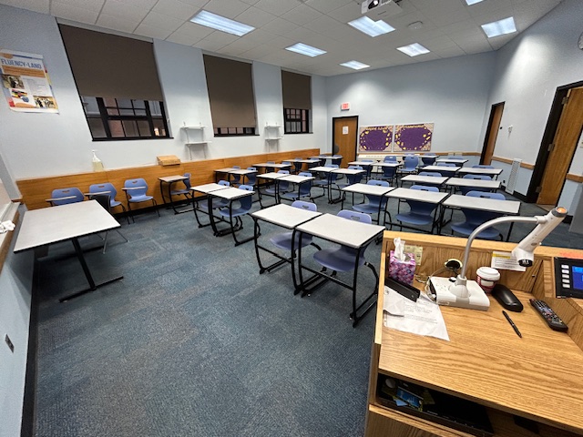 Back of the classroom with student desks and chairs.