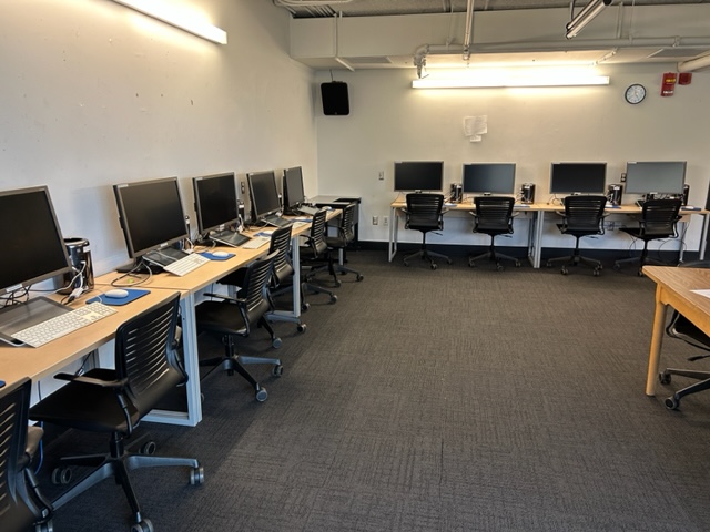 Student computer desks with wacom boards lined on the back wall.