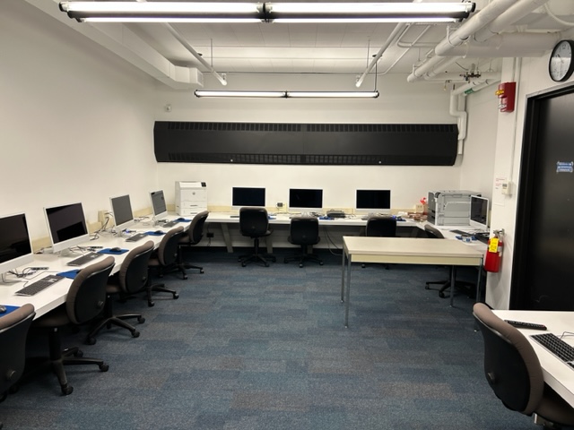 Student computer desks and chairs lined up on the wall.