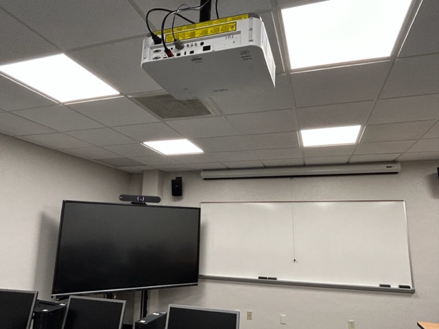 Front of the classroom with a smart board, a whiteboard and projector.
