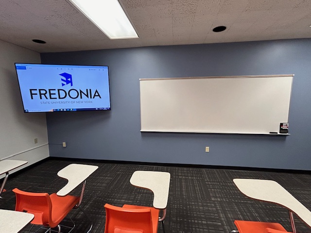 Front of the classroom with a large whiteboard and tv.