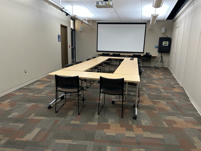 Conference Room with tables, chairs, and a projector screen.