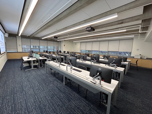 Back of the classroom with computer desks in rows.
