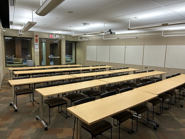 Back of the classroom with student desks arranged in rows and windows on the back wall