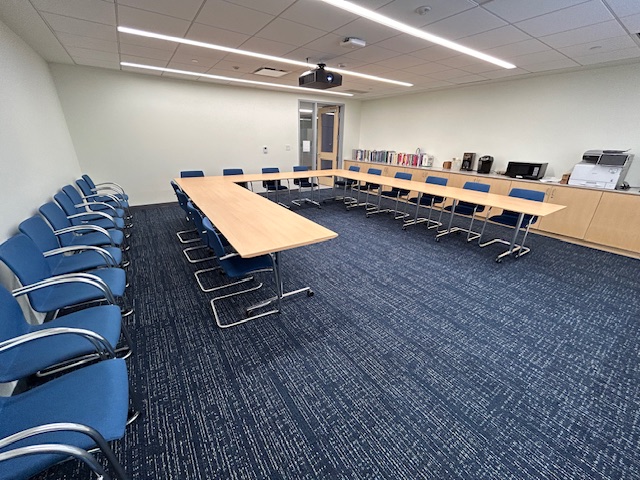 Back of the conference room with large tables and several chairs