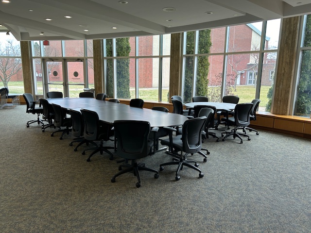 Back of the conference room with tables and chairs and large windows on the back wall.