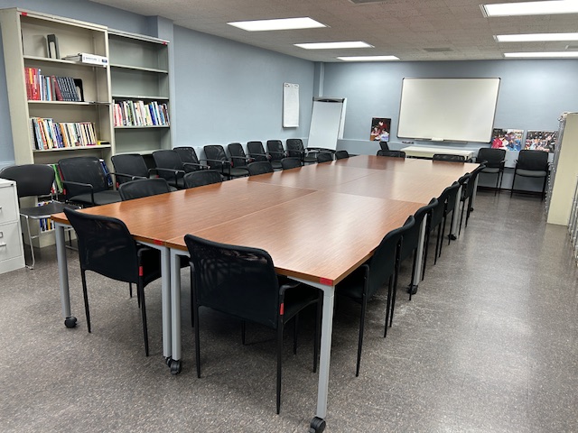 Back of the conference room with a large white board and several tables and chairs.